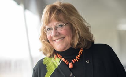Ruth D. in business attire smiling at the camera with a neutral background.